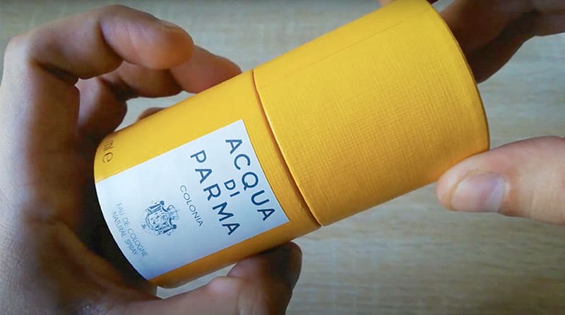 A close-up in the hands of the Acqua Di Parma Colonia yellow colored hatbox packaging.