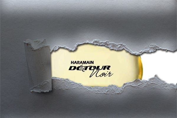 A bottle of Al Haramain Detour Noir partly revealed through some torn paper