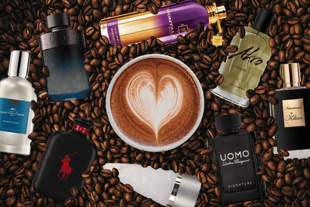 A cup of latte with a heart formed on the top sitting on dark roasted coffee beans with a selection of 8 different coffee scented cologne bottles surrounding it.