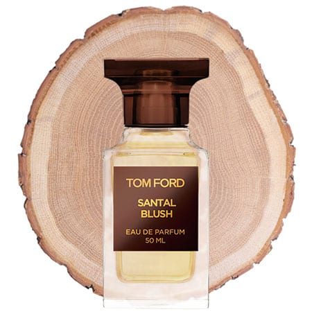 A bottle of Tom Ford Santal Blush in front of the fresh cut end face of a wooden log.