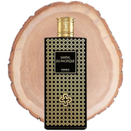 A bottle of Perris Monte Carlo Santal Du Pacifique EDP in front of the fresh cut end face of a wooden log.