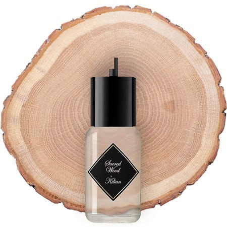 A 50 ml refill bottle of Kilian Sacred Wood in front of the fresh cut end face of a wooden log.