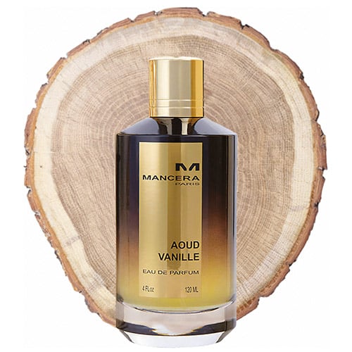 A bottle of Mancera Aoud Vanille in front of the fresh cut end face of an oud wooden log.