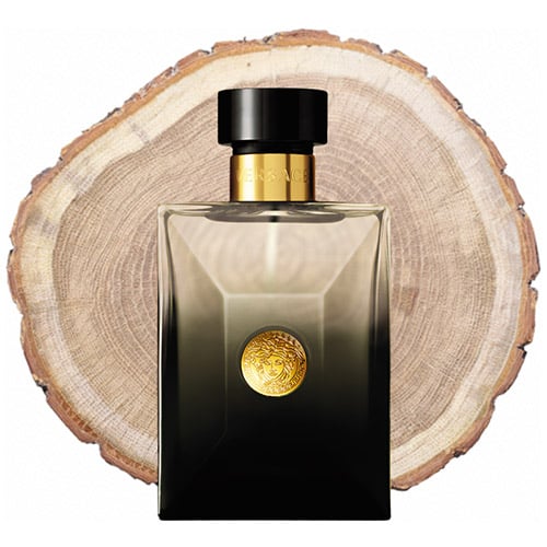 A bottle of Versace Oud Noir in front of the fresh cut end face of an oud wooden log.