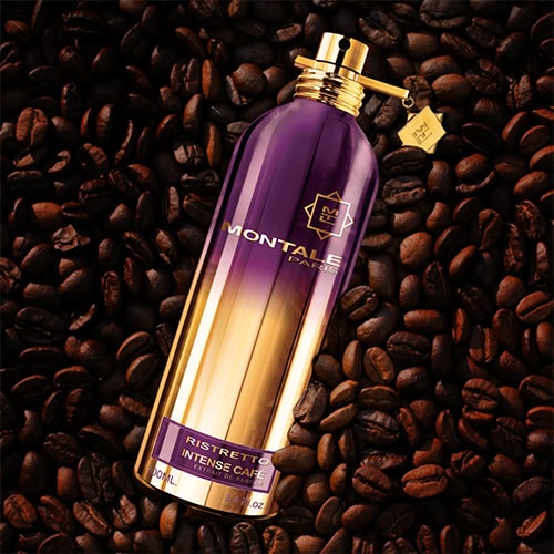 A bottle of Montale Ristretto Intense Café placed faceup on top of a pile of dark roasted coffee beans.