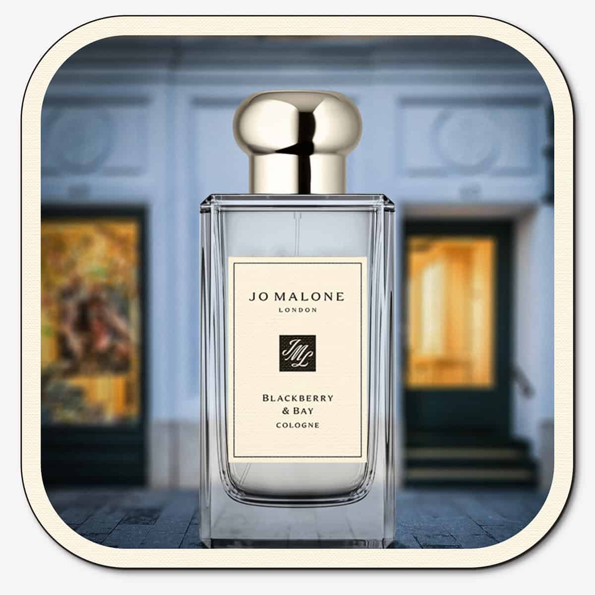 A close-up of the front face of a bottle of Jo Malone Blackberry & Bay Cologne. The bottle is placed on the ground with the Jo Malone global flagship storefront in 
London in the background.