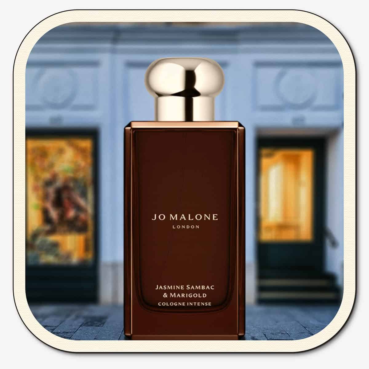 A close-up of the front face of a bottle of Jo Malone Jasmine Sambac & Marigold Cologne Intense. The bottle is placed on the ground with the Jo Malone global flagship storefront in 
London in the background.