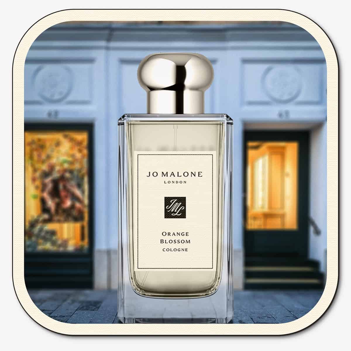 A close-up of the front face of a bottle of Jo Malone Orange Blossom Cologne. The bottle is placed on the ground with the Jo Malone global flagship storefront in 
London in the background.