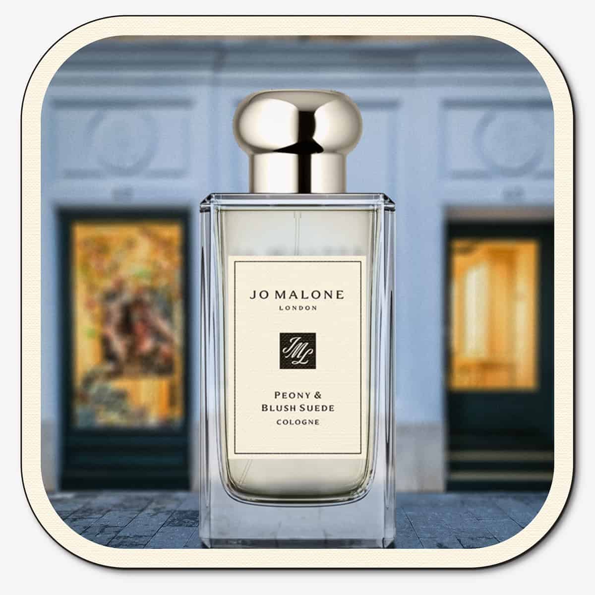 A close-up of the front face of a bottle of Jo Malone Peony Blush & Suede Cologne. The bottle is placed on the ground with the Jo Malone global flagship storefront in 
London in the background.