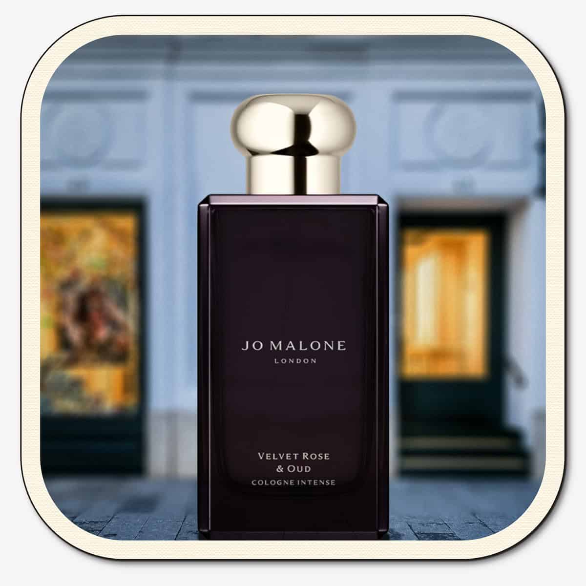 A close-up of the front face of a bottle of Jo Malone Velvet Rose & Oud Cologne Intense. The bottle is placed on the ground with the Jo Malone global flagship storefront in 
London in the background.