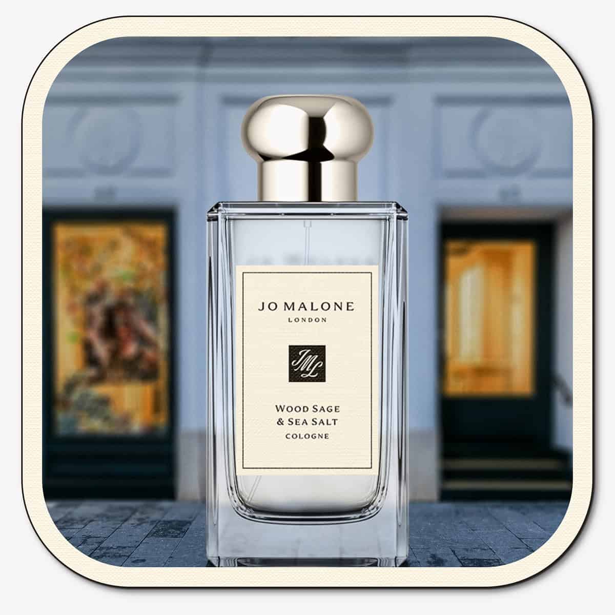 A close-up of the front face of a bottle of Jo Malone Wood Sage & Sea Salt Cologne. The bottle is placed on the ground with the Jo Malone global flagship storefront in 
London in the background.