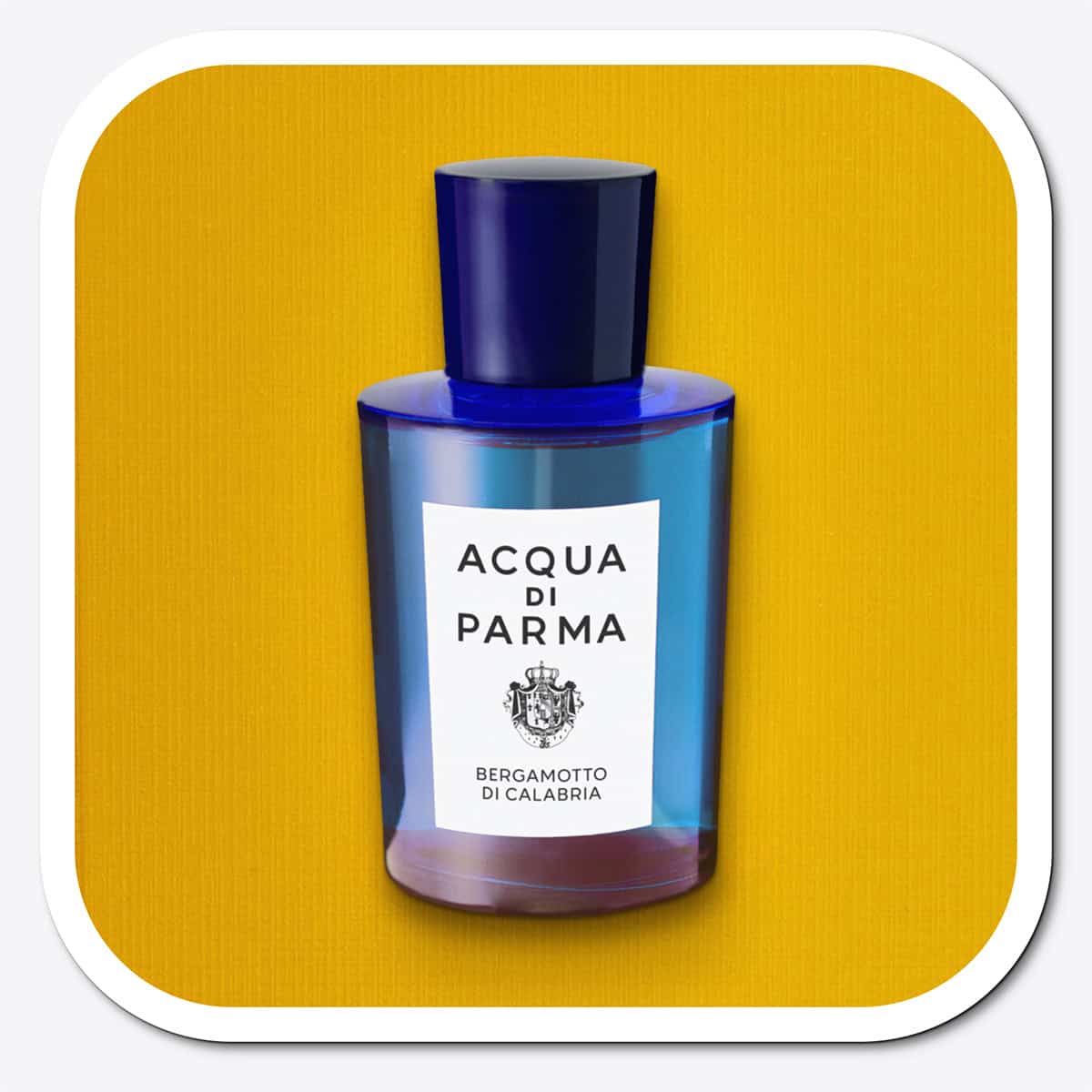 A close-up of the front face of a bottle of Acqua Di Parma Bergamotto Di Calabria. The bottle is placed on its side, label side up, and is resting on a yellow-colored textured surface.