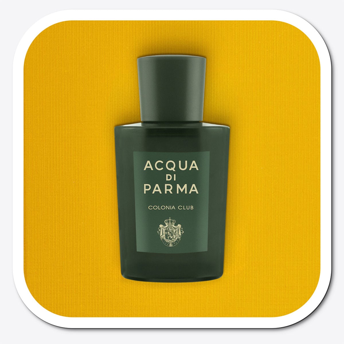 A close-up of the front face of a bottle of Acqua Di Parma Colonia Club. The bottle is placed on its side, label side up, and is resting on a yellow-colored textured surface.
