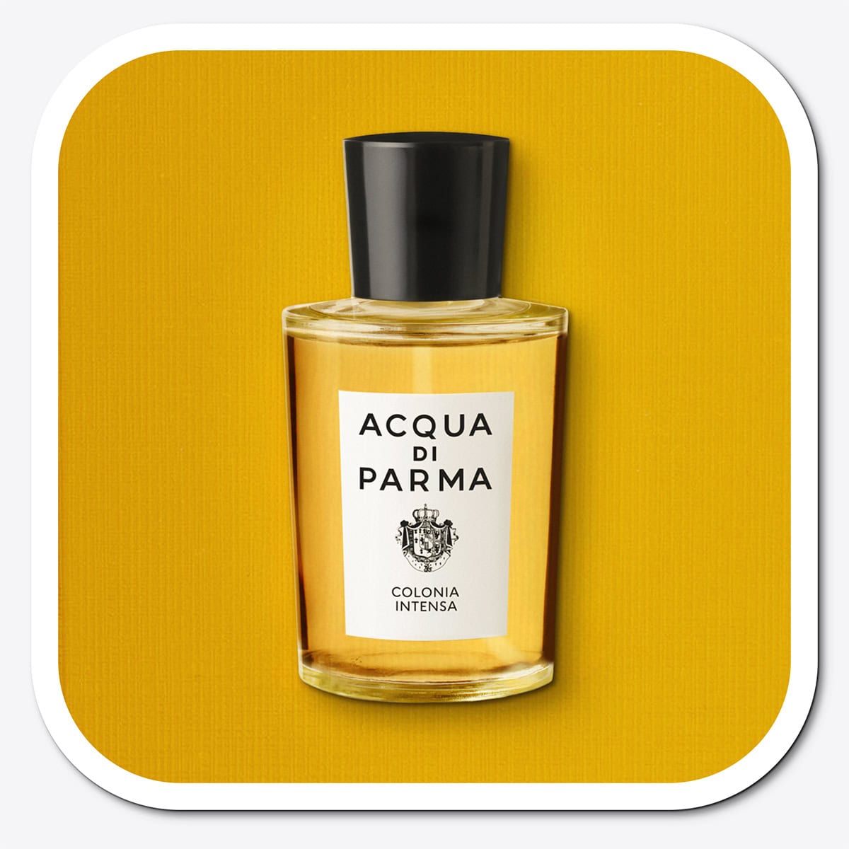 A close-up of the front face of a bottle of Acqua Di Parma Colonia Intensa. The bottle is placed on its side, label side up, and is resting on a yellow-colored textured surface.